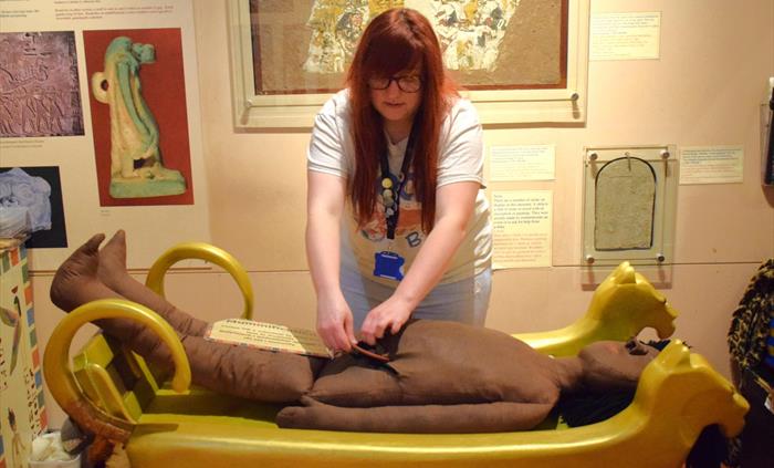 Egypt Centre Volunteer performing Mummification upon the museum's dummy mummified person.